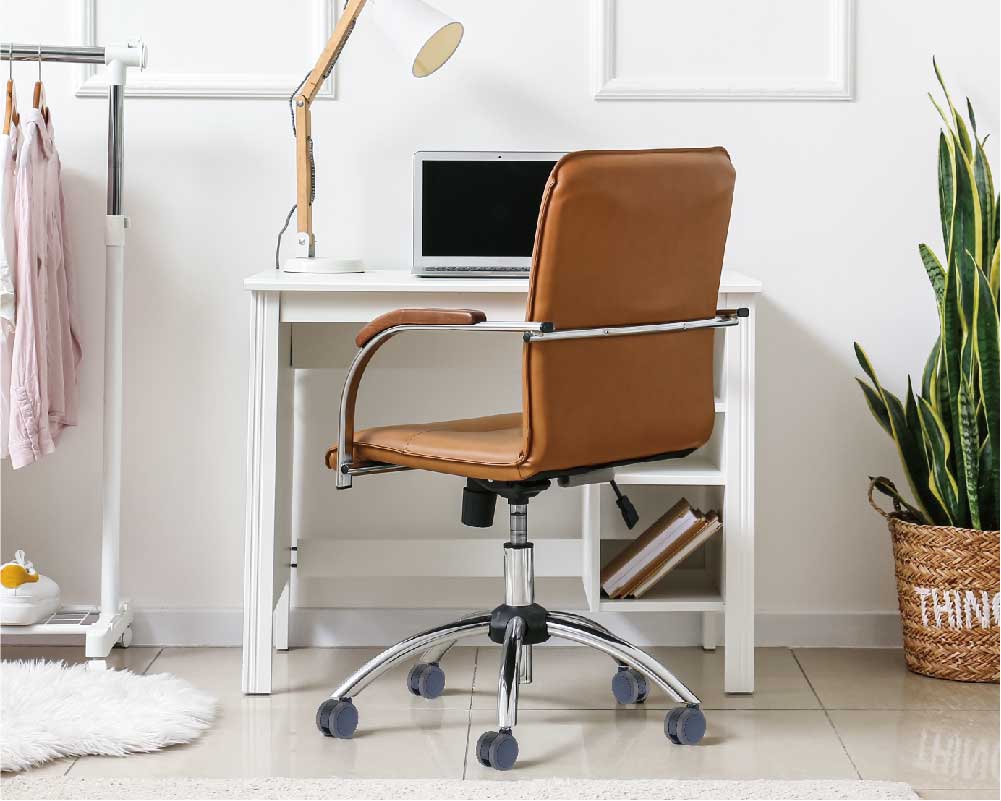 Modern office setup with a black and orange ergonomic chair on caster wheels in front of a wooden desk with a computer and office supplies.