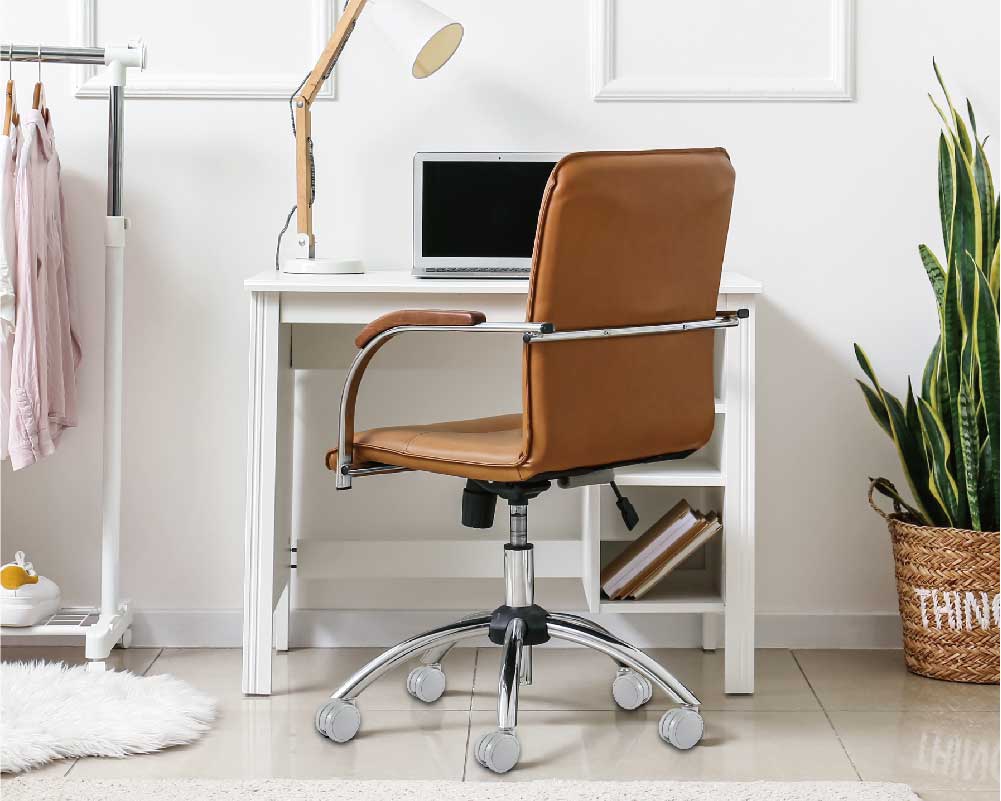 Modern office setup with a black and orange ergonomic chair on caster wheels in front of a wooden desk with a computer and office supplies.