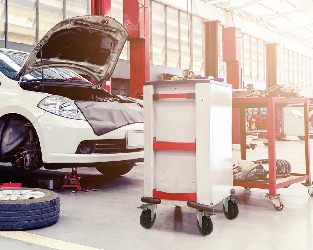 Automotive workshop with tool cart on equipment casters beside a car