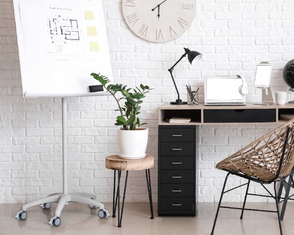 Home office setup with flip chart on casters and potted plant